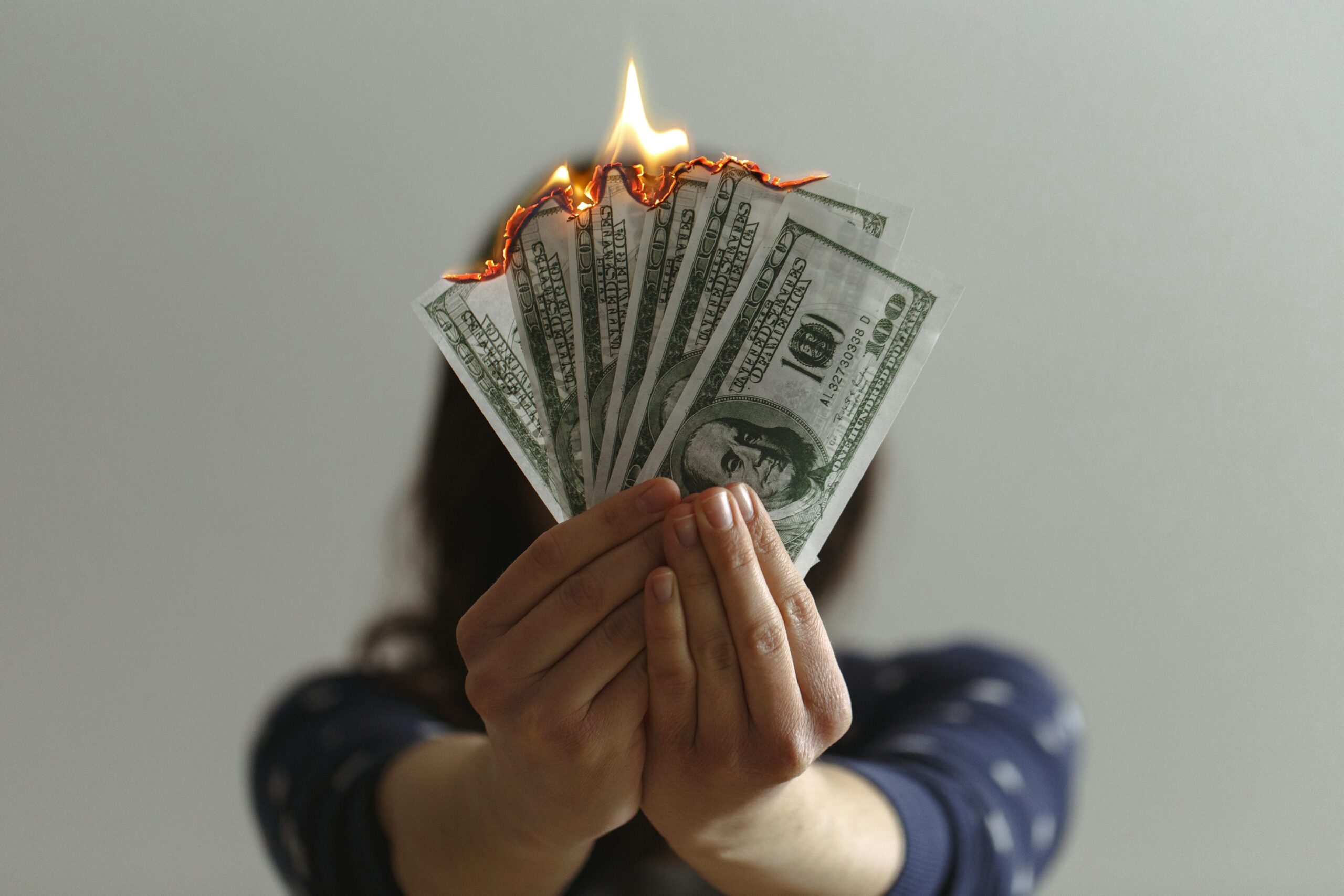 a woman holding several banknotes which are on fire